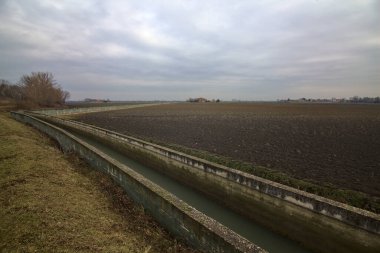 Kışın İtalya 'nın kırsal kesimindeki tarlalı bir arazide bir su kanalı.