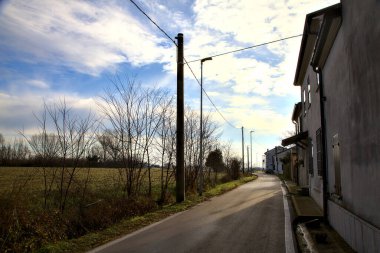 Evlerin yanındaki yol ve kışın İtalya kırsalında bir tarla.