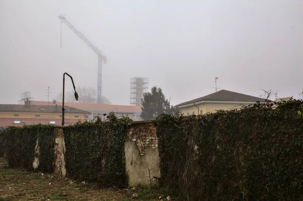 Muro Límite Con Hiedra Silueta Edificios Una Grúa Distancia Niebla — Foto de Stock
