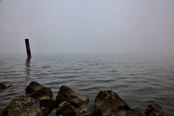 意大利小镇郊外的一个公园里 在一个多雾的日子里 在湖畔的水面上有一根木制的杆子 — 图库照片