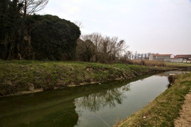 Terk edilmiş kır köşkü, kışın İtalya kırsalında bir su deresinin yanında.