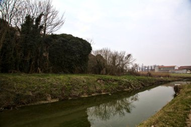 Terk edilmiş kır köşkü, kışın İtalya kırsalında bir su deresinin yanında.