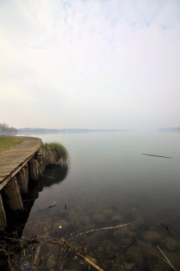 Kışın sisli bir günde Jetty gölün kıyısında