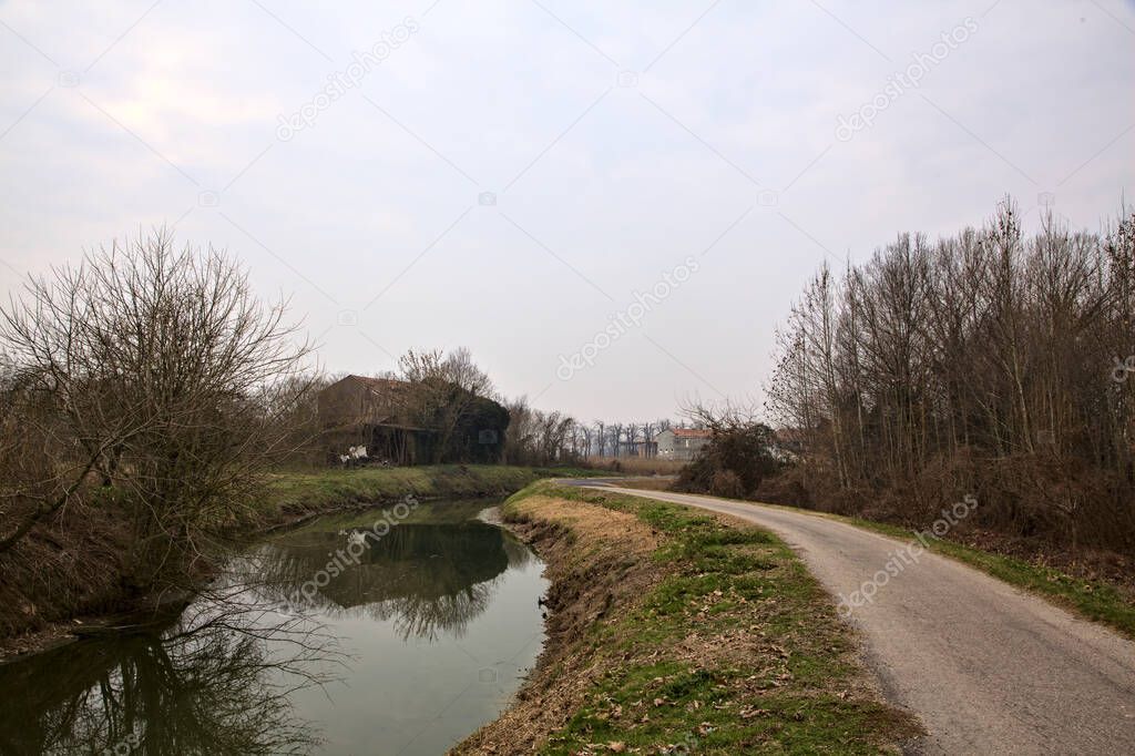 Bike lane next to a stream of water and fields in the italian countryside in winter