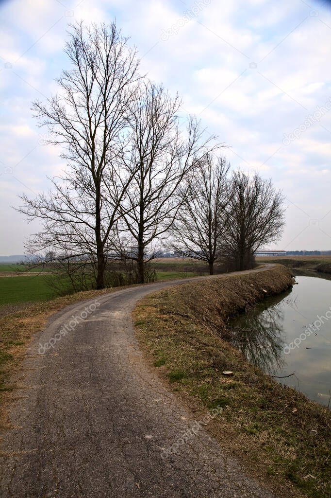 Bike lane next to a stream of water and fields in the italian countryside in winter