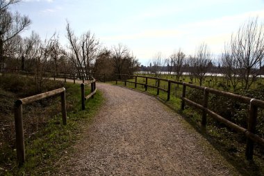 İtalya kırsalında bir gölün yanında çakıl patikası