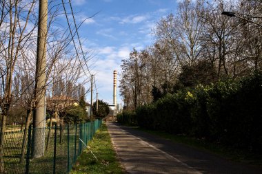 Uzakta bir baca yığınıyla İtalya kırsalında yol