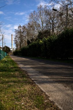 Uzakta bir baca yığınıyla İtalya kırsalında yol