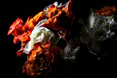 Siyah arka planda turuncu ve beyaz güller.