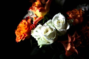 Siyah arka planda turuncu ve beyaz güller.