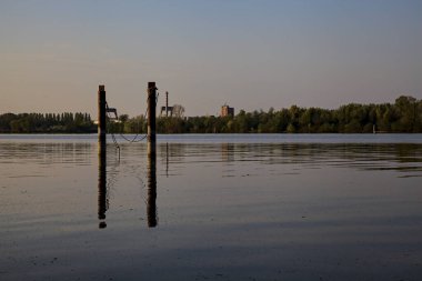 Gölde demirleyen direkler, yansımaları suya dökülür.
