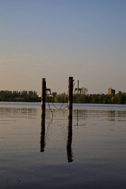 Gölde demirleyen direkler, yansımaları suya dökülür.