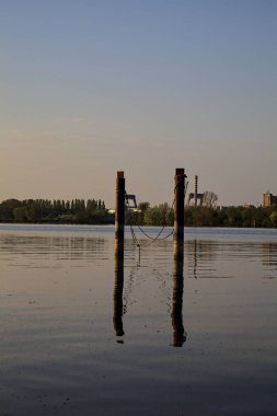 Gölde demirleyen direkler, yansımaları suya dökülür.
