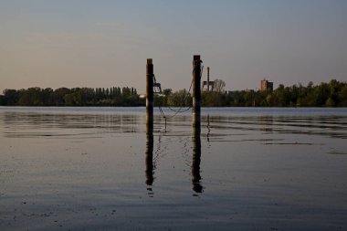 Gölde demirleyen direkler, yansımaları suya dökülür.