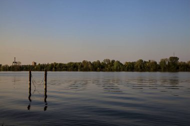 Gölde demirleyen direkler, yansımaları suya dökülür.