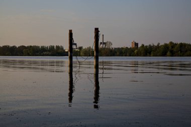 Gölde demirleyen direkler, yansımaları suya dökülür.