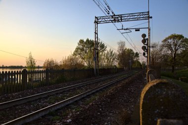 Gün batımında göl kenarındaki bir barajın üstündeki tren yolu.