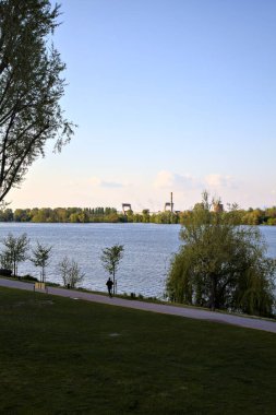 Baharın açık bir gününde, gölün kıyısındaki insanlar