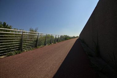 Beton bir duvarın oluşturduğu gölgeli kırmızı betonla bisiklet yolu