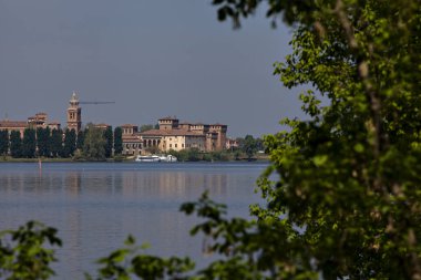 Baharda açık bir günde Mincio nehrinin yanında kaleler ve kiliseler olan gökyüzü.