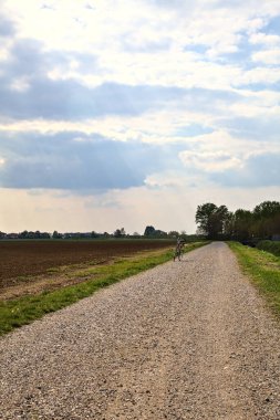 İlkbaharda İtalya 'nın kırsal kesimindeki tarlaların yanındaki çakıl yolu.