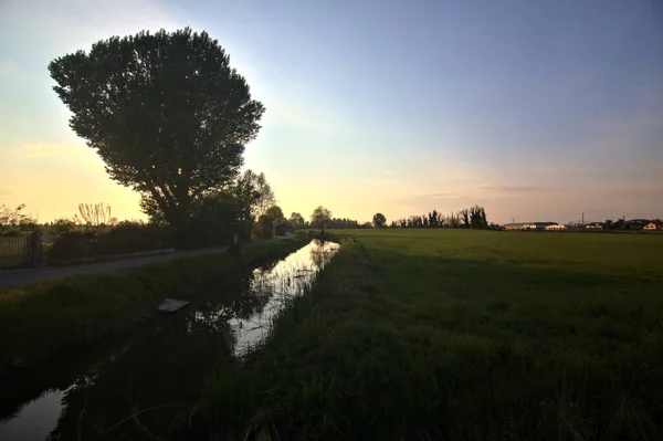 Estrada Campo Pôr Sol Delimitada Por Riacho Água — Fotografia de Stock