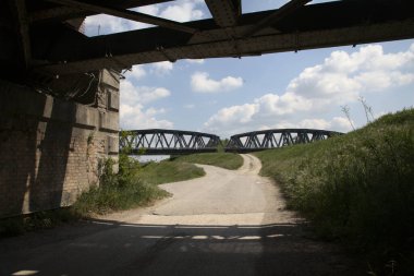 İtalya 'nın kırsal kesimindeki demiryolu köprüsü aşağıdan görülüyor ve bir köprü tarafından çerçeveleniyor.