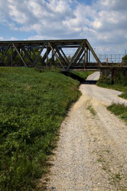 Road that passes under a railway bridge on a clear day in spring in the italian countryside