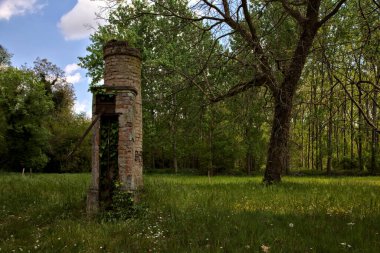 Remains of a manual water pump in the middle of a field in a park