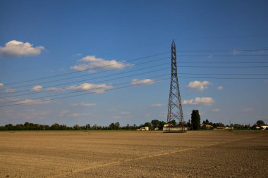 İtalya 'nın kırsal kesiminde açık bir günde ortasında elektrik direği olan tarla sürmüş.