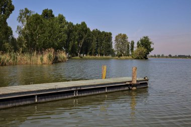 Arka planda uzanan bir kıyısı olan bir nehre demirlemek