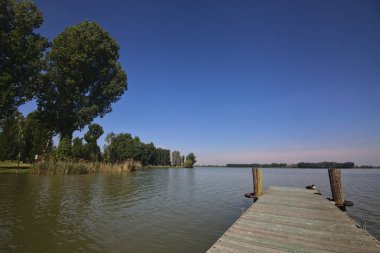 Arka planda uzanan bir kıyısı olan bir nehre demirlemek