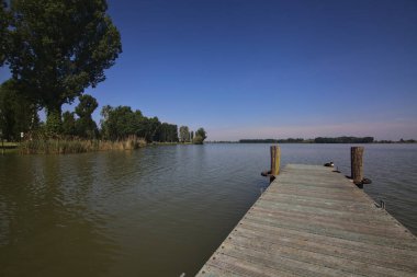 Arka planda uzanan bir kıyısı olan bir nehre demirlemek