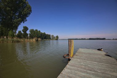 Arka planda uzanan bir kıyısı olan bir nehre demirlemek