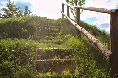 Tahta merdiven, güneş tarafından aydınlatılan bir toprak formasyonu tezgahında.