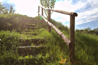 Tahta merdiven, güneş tarafından aydınlatılan bir toprak formasyonu tezgahında.