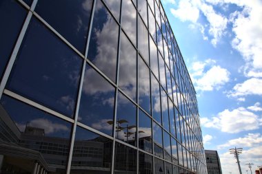 Gökyüzü bir binanın cam cephesinde bulutlarla kaplı.