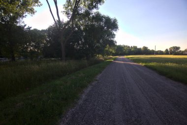 Gün batımında İtalya kırsalının gölgesinde bir tarla ile çevrili bir köy yolu.