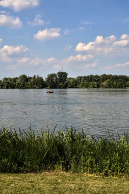 Fishing boat with people on a lake seen from the distance at sunset in summer