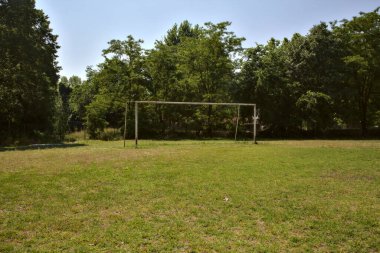Empty football field with a goal in a park at noon