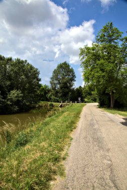 Yazın İtalya kırsalında bir su deresinin yanında bisiklet yolu.