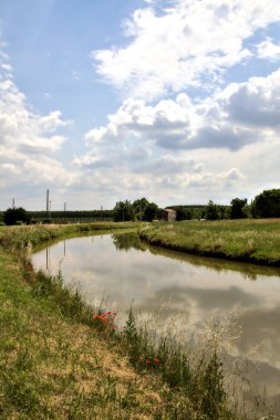 Yazın İtalya kırsalındaki bir köyün varoşlarındaki bir su deresinin yanında bisiklet yolu.