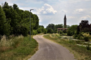 Yazın İtalya kırsalında bisiklet yolu. Uzakta çan kulesi var.