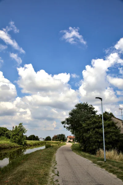 Yazın İtalya kırsalındaki bir köyün varoşlarındaki bir su deresinin yanında bisiklet yolu.