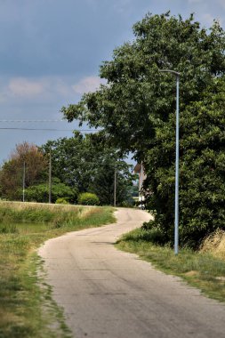 Yazın İtalya kırsalındaki bir köyün varoşlarındaki bir su deresinin yanında bisiklet yolu.