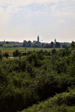 İtalya 'nın kırsal kesimlerinde yaz aylarında bir köy ve çan kulesi olan tarlalar.