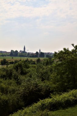 İtalya 'nın kırsal kesimlerinde yaz aylarında bir köy ve çan kulesi olan tarlalar.