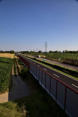 Kırsal kesimdeki İtalyan otoyolu yazın günbatımında bir köprünün üstünden görülüyor.