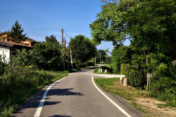 夏の日没時にカントリーハウスのグループの真ん中の田舎の道路 — ストック写真