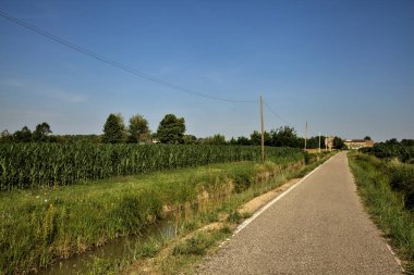 Tarlalı köy yolu ve yaz sonunda günbatımında terk edilmiş bir malikane.
